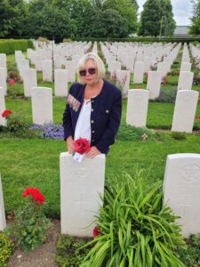 A photograph showing the former Mayor of Crewe standing by a Normandy war grave with a poppy